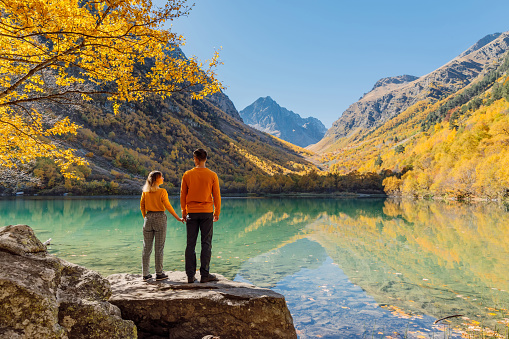 Happy couple at crystal lake in the autumnal mountains. Mountain lake and couple hikers