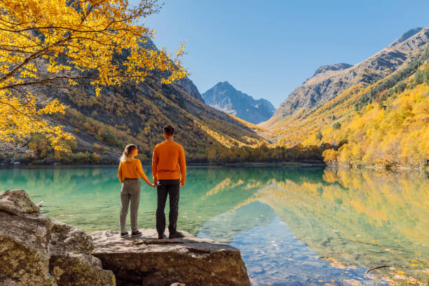 Happy couple at crystal lake in the autumnal mountains. Mountain lake and couple hikers Happy couple at crystal lake in the autumnal mountains. Mountain lake and couple hikers fall travel stock pictures, royalty-free photos & images