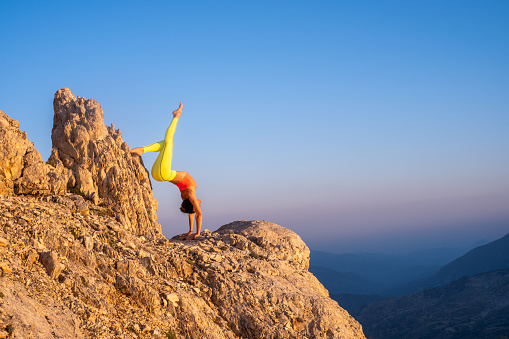 Woman makes exercises of yoga, the top of the mountain.