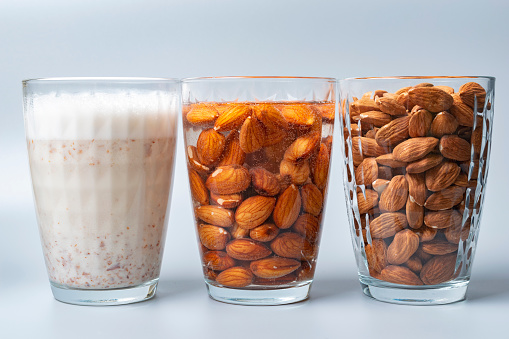 Glasses with dry, soaked almonds and with almonds milk. Showing ingredients needed to prepare almonds milk.