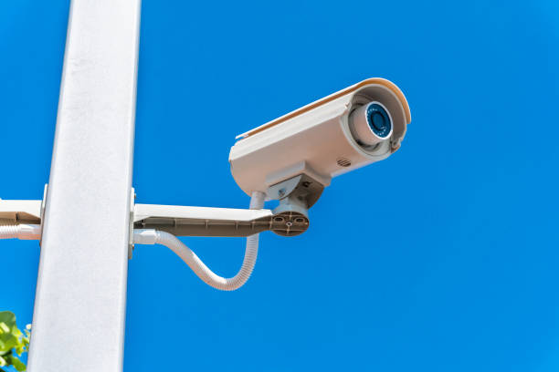 istock Digital surveillance camera is mounted on a pole with the blue sky in the background. 1329504918