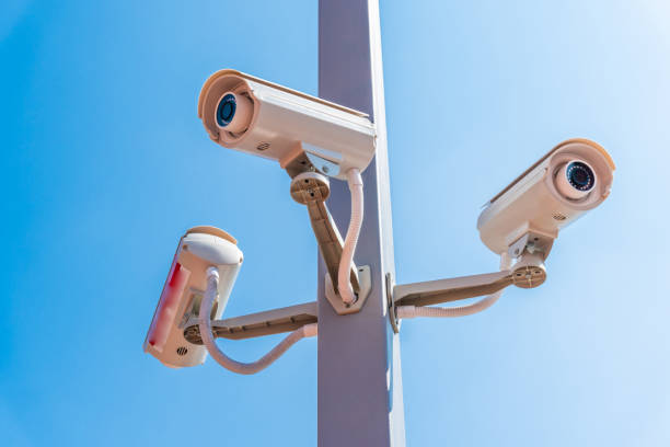 istock Digital surveillance camera is mounted on a pole with the blue sky in the background. 1329505100