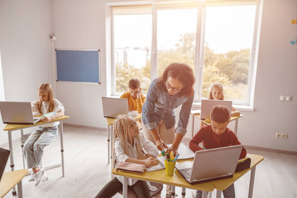 istock Smiling teacher explaining the task to schoolchildren at school 1329507644