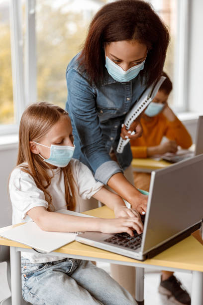 little girl in mask using laptop during lesson - pre adolescent child child group of people little boys imagens e fotografias de stock