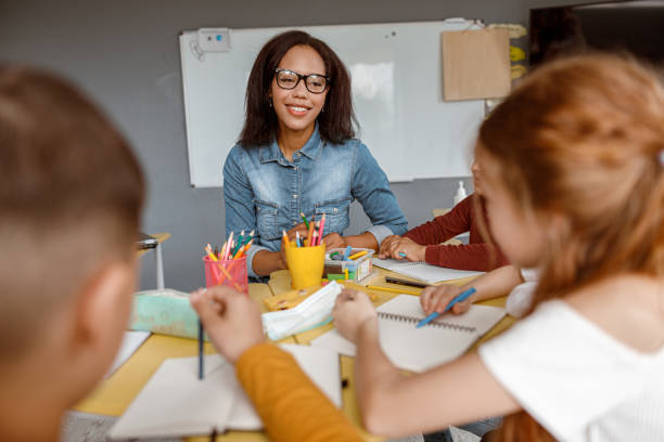 istock Young teacher talking with kids during the lesson in the classroom 1329507684