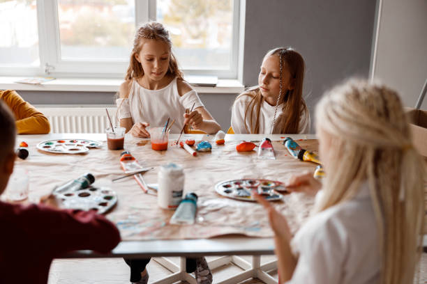 istock Classmates painting on paper with colorful paints 1329507765