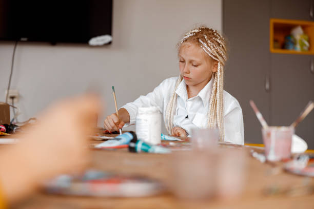 istock Kid learning to paint with watercolors at school 1329507770