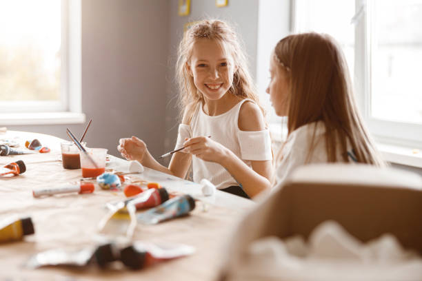 istock Two girlfriends talking while painting with watercolors at school 1329507772