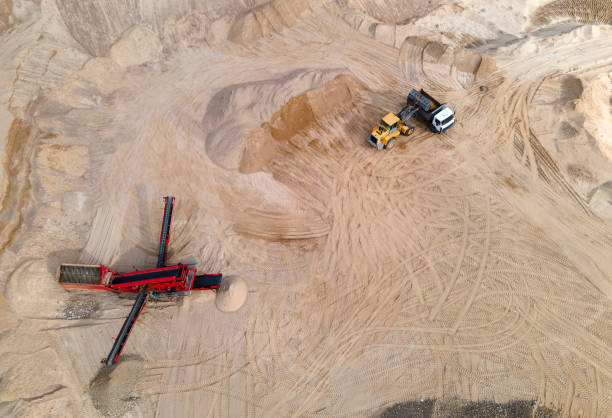 istock Arial view of the open pit mine. Front end loader loading gravel into stone jaw crusher in open-pit. 1329507975