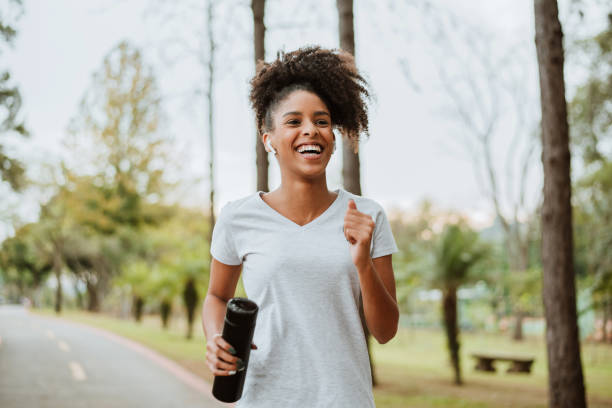 frau, die im park läuft - african descent healthy lifestyle people water stock-fotos und bilder