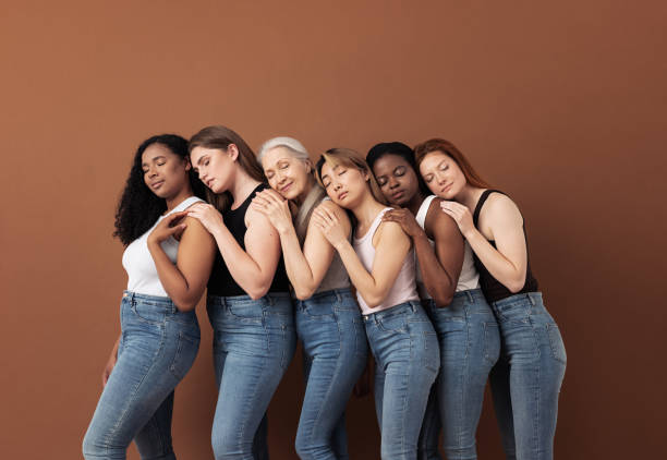 istock Diverse women in casuals embracing each other while standing with closed eyes over brown background 1329511512