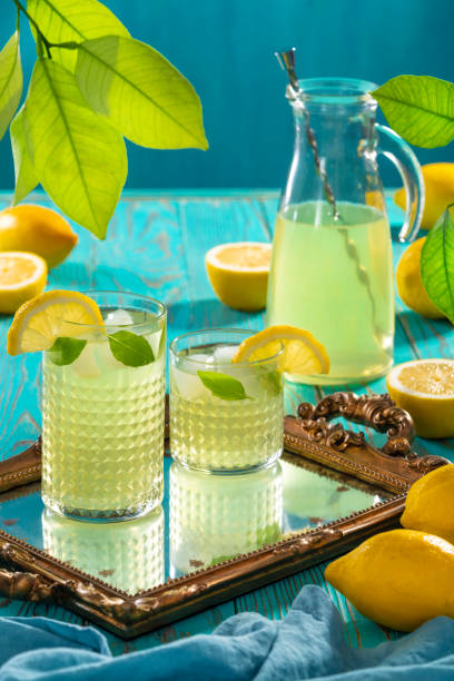 istock Lemonade Jar with two glasses and ice cubes refreshing summer on turquoise background 1329513113