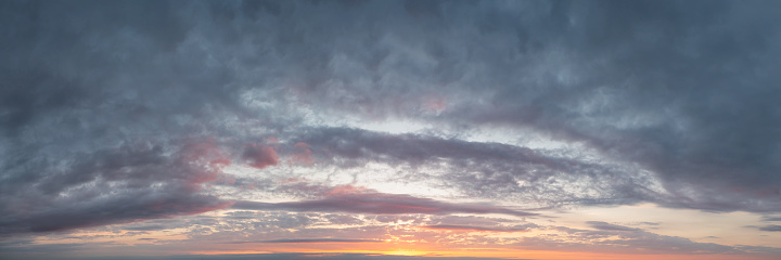 A sky darkening with clouds at sunset. Panoramic skyscape in 1:3 format.