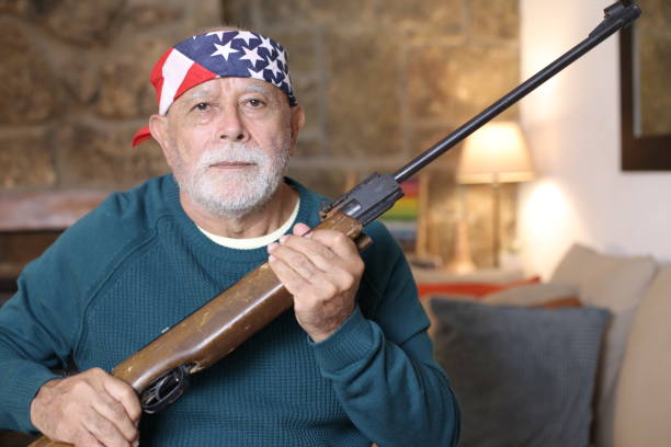 Senior American man holding a weapon at home.