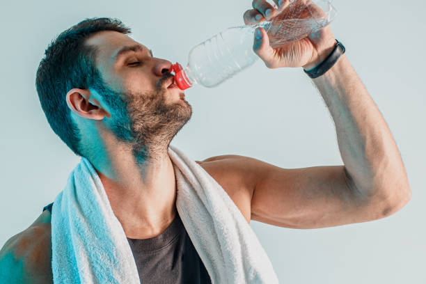 istock Tired young sportsman drinking water from bottle 1329516981