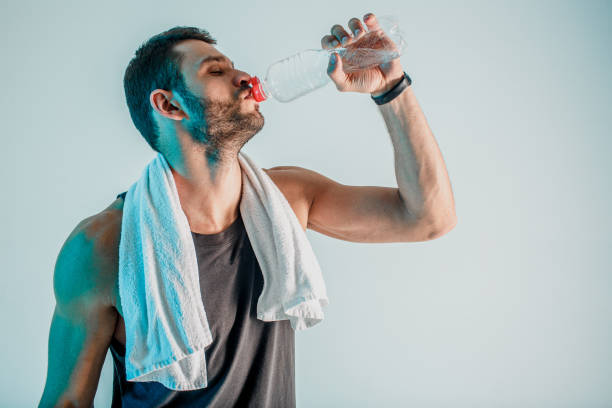 istock Tired young sportsman drinking water from bottle 1329516991
