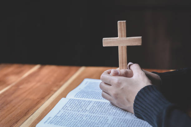istock The woman holds the cross and prayes with her scriptures on the table. 1329517761