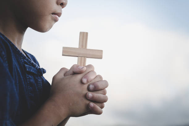 kinder beten gott an, indem sie das christliche kreuz halten, ein christliches konzept. - praying god love wisdom stock-fotos und bilder