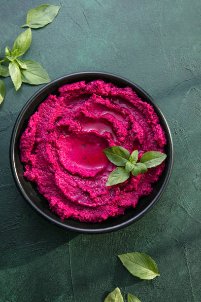 istock Humus Bowl. Red beetroot hummus with fresh vegetables, olive oil on table 1329518688