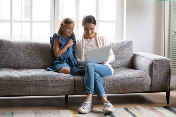istock Smiling mom and small daughter use laptop at home 1329519465