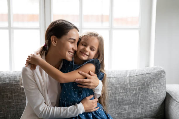 istock Happy small daughter hug smiling mom at home 1329519489