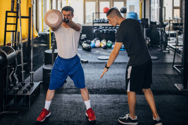 istock Man exercises with personal trainer in gym 1329520053