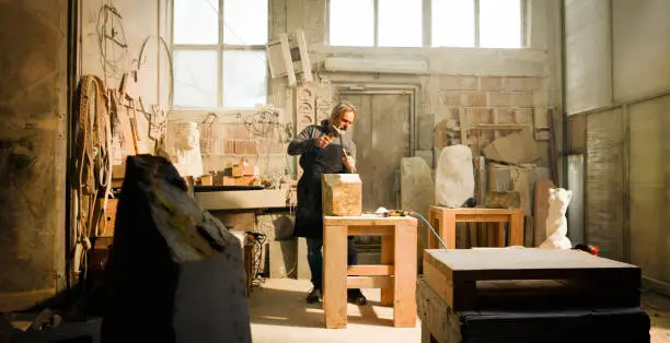 Photo of Stonemason chiselling a block of stone in workshop