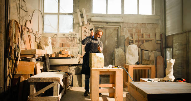 istock Stonemason chiselling a block of stone in workshop 1329520125