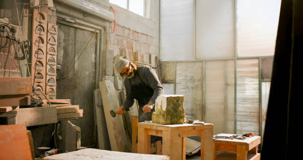 istock Stonemason chiselling a block of stone in workshop 1329520157
