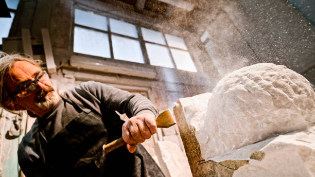 istock Stonemason chiselling away chunks of white stone 1329520344