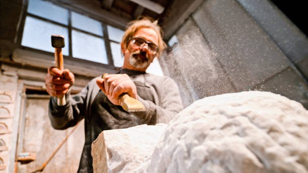 istock Stonemason chiselling away chunks of white stone 1329520358
