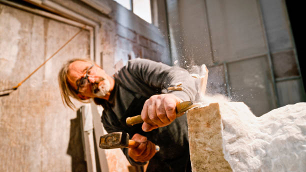 istock Stonemason chiselling away chunks of white stone 1329520359