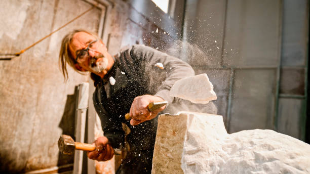 istock Stonemason chiselling away chunks of white stone 1329520362
