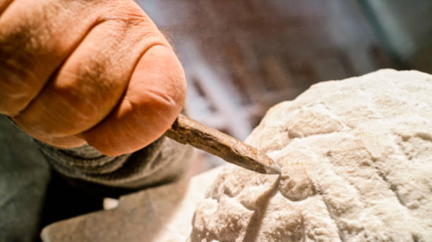 istock Stonemason chiselling surface of white stone 1329520372