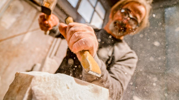 istock Stonemason chiselling away chunks of white stone 1329520374