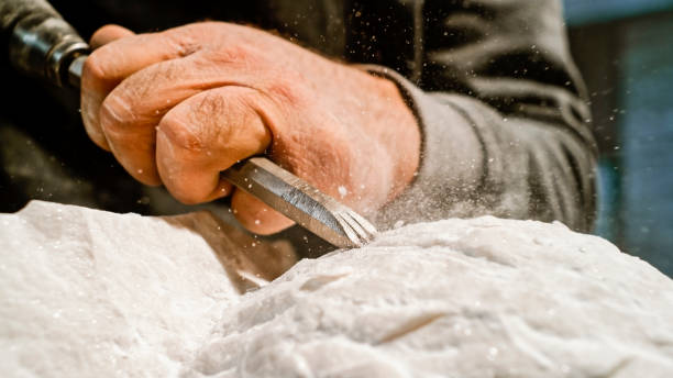istock Stonemason chiselling surface of white stone 1329520375