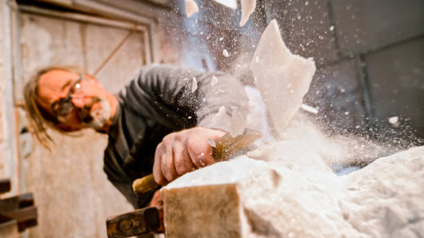 istock Stonemason chiselling away chunks of white stone 1329520390