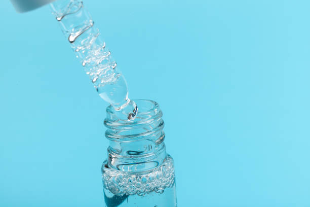 istock face serum drop with bottle on blue background. 1329521694