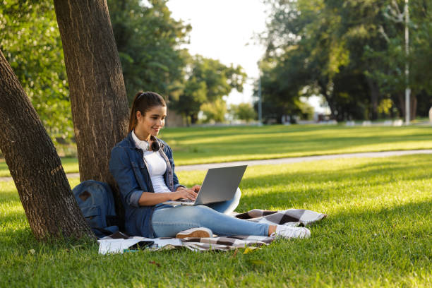istock Beautiful young woman student in the park using laptop computer. 1329521871