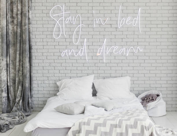 Light loft bedroom with neon sign Light loft bedroom with neon sign stay in bed and dream on a grey brick wall neon bedroom stock pictures, royalty-free photos & images