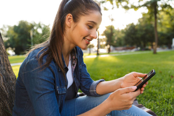 istock Beautiful young woman student in the park using mobile phone. 1329522811