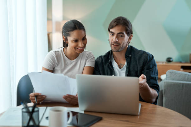 istock Shot of a young couple doing paperwork while using a laptop at home 1329523043