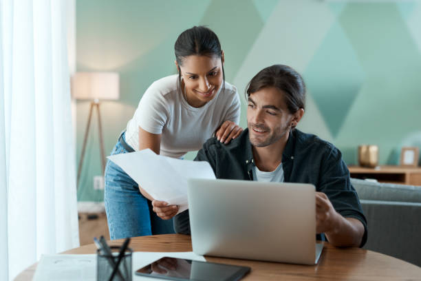 istock Shot of a young couple doing paperwork while using a laptop at home 1329523046