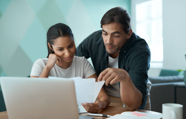 istock Shot of a young couple doing paperwork while using a laptop at home 1329523047