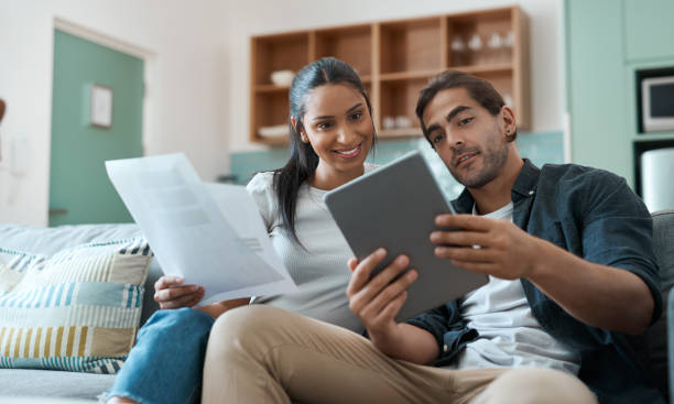istock Shot of a young couple doing paperwork while using a digital tablet at home 1329523076