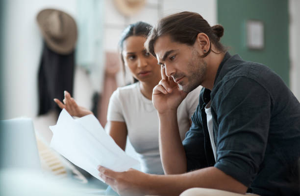 shot of a young couple having an argument while doing paperwork at home - failure relationship difficulties computer women imagens e fotografias de stock