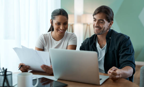 istock Shot of a young couple doing paperwork while using a laptop at home 1329523145