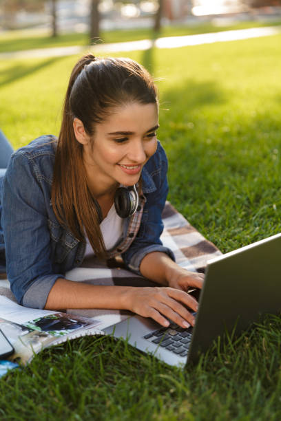 istock Beautiful young woman student in the park using laptop computer. 1329523229