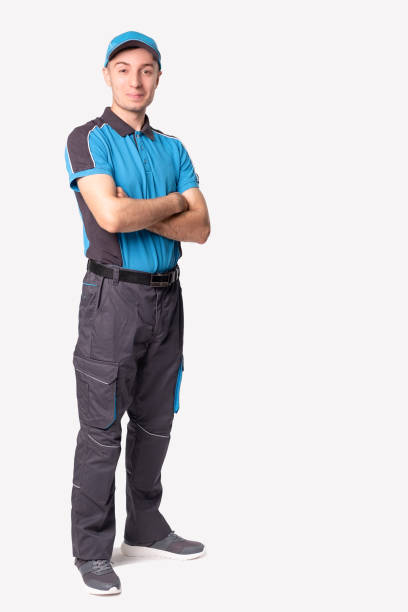 istock On time delivery service. Young logistic bearded man in blue uniform standing with folded hands and smiling. 1329524486