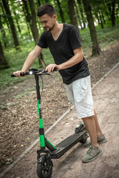 istock Attractive man riding electric kick scooter at cityscape park. 1329525683